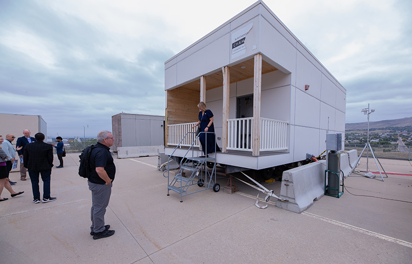 Shanti Pless speaks to a group of people in front of a modular apartment prototype.