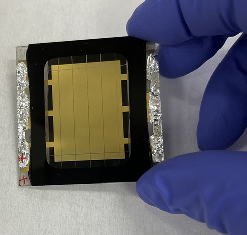 A gloved hand holds a perovskite solar cell.