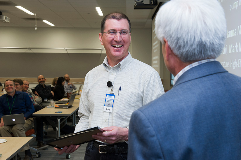 A person smiles while receiving an award in front of a group of people.