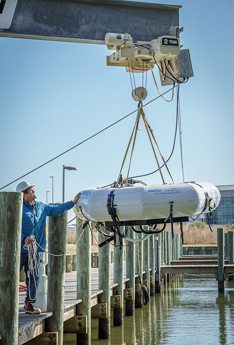 A machine lifts a device onto a pier.