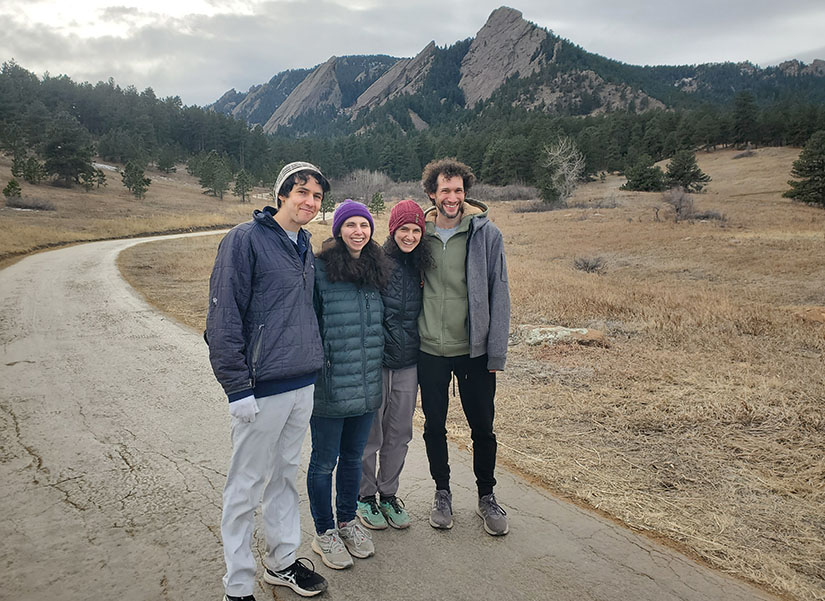 Four people stand on a hiking trail.