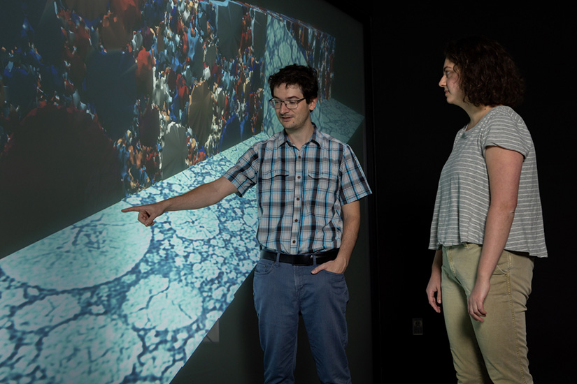 Two people look at a screen in a visualization lab.