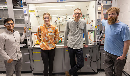 Continue reading about Four people stand in front of laboratory equipment.