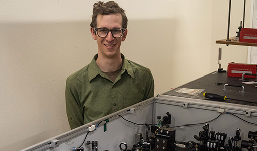 Continue reading about A researcher poses behind a table in a lab.