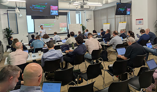 Continue reading about A large room full of people seated while watching a speaker present information