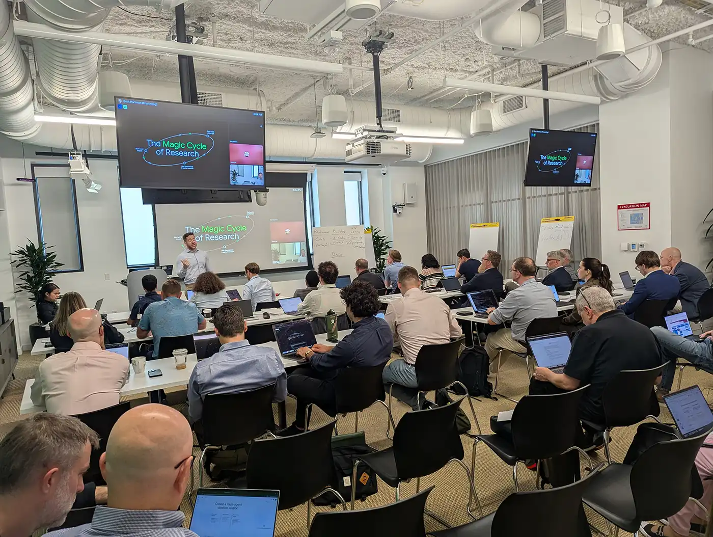 A large room full of people seated while watching a speaker present information