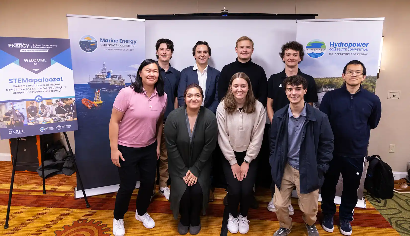 Nine people pose for a group photo next to STEMapalooza posters.