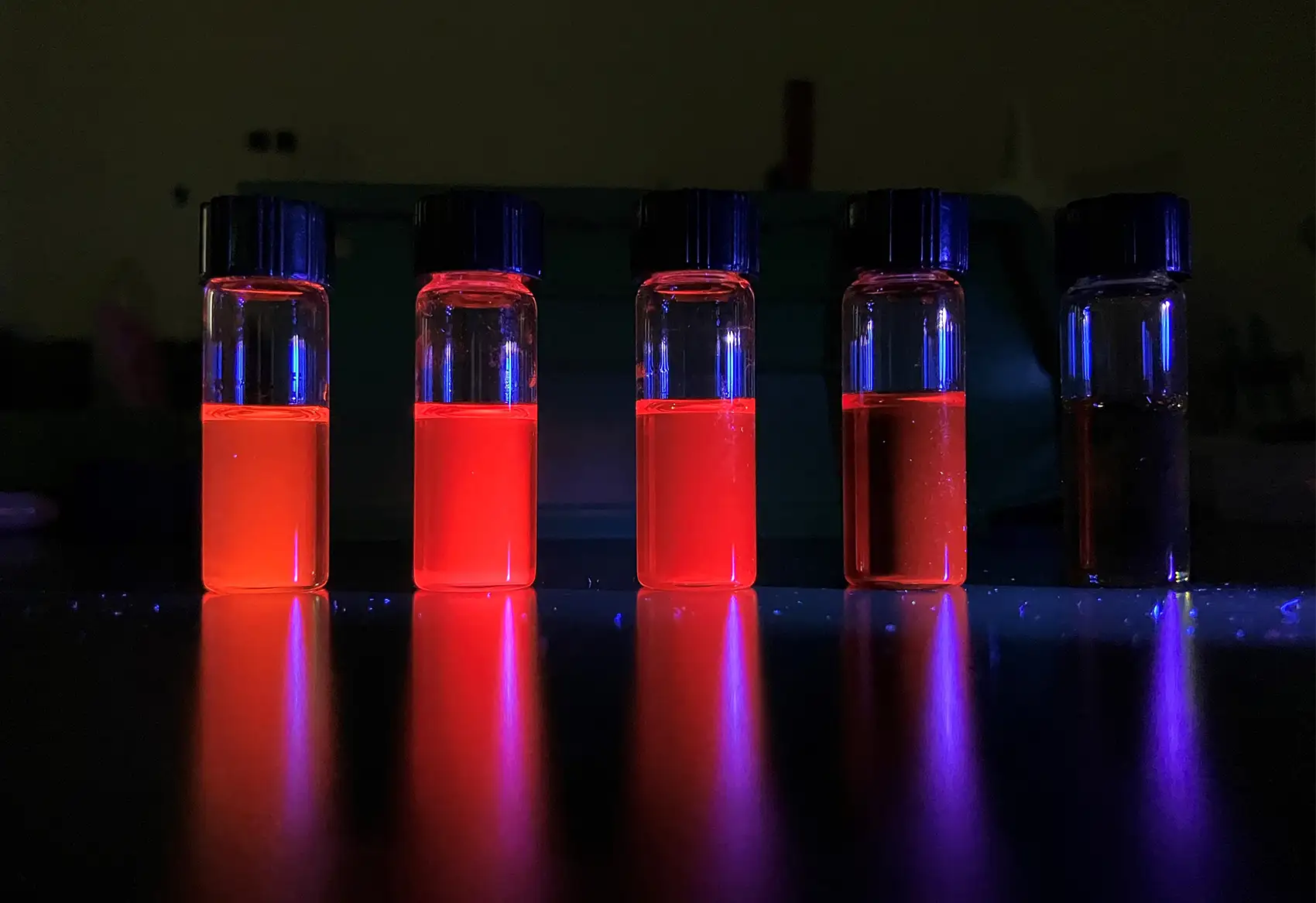 Image of five vials with glowing liquid inside.