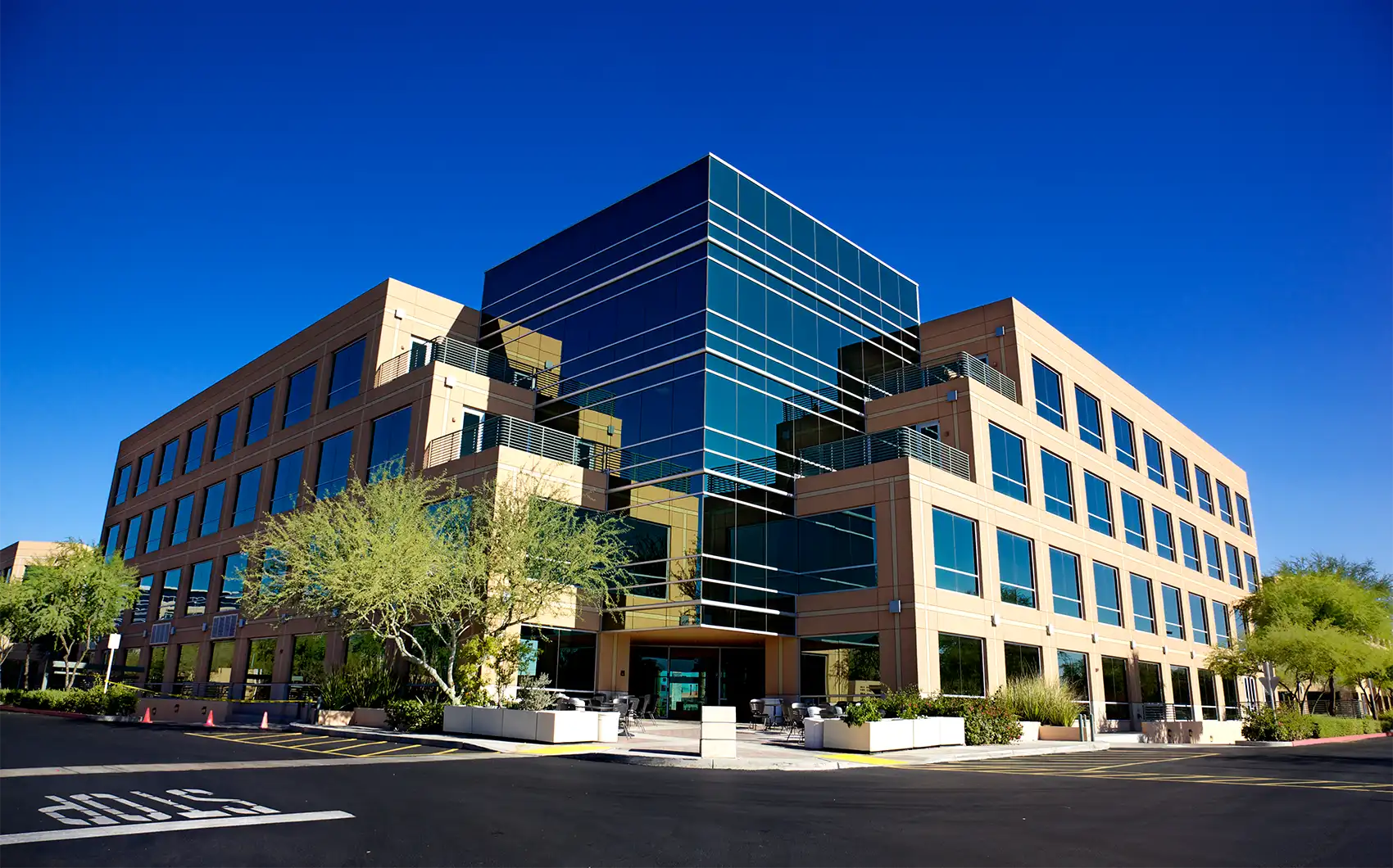 An office building on a sunny day surrounded by trees.