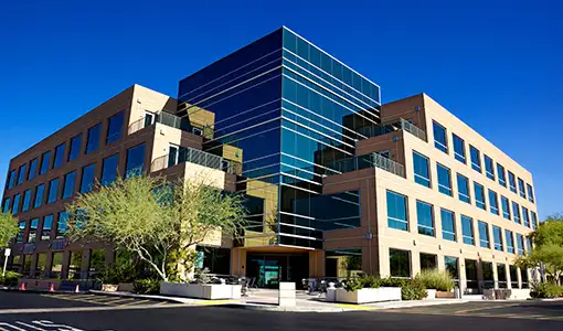 Continue reading about An office building on a sunny day surrounded by trees.