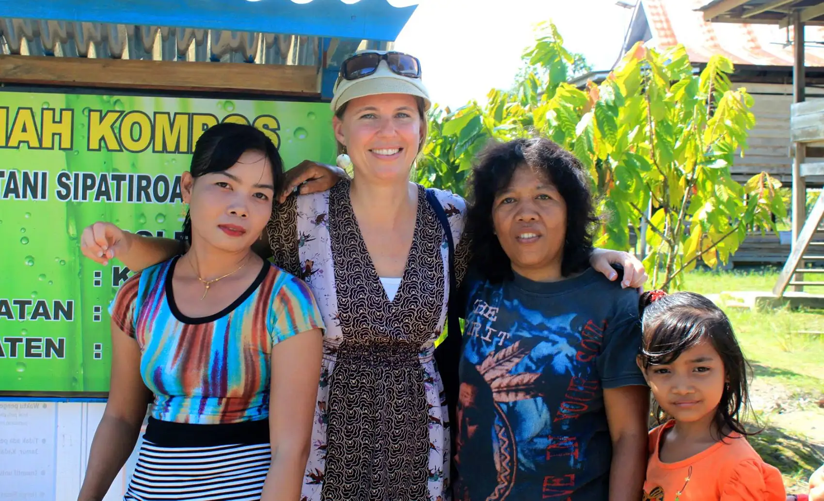 Three adults and a child stand in front of a sign.