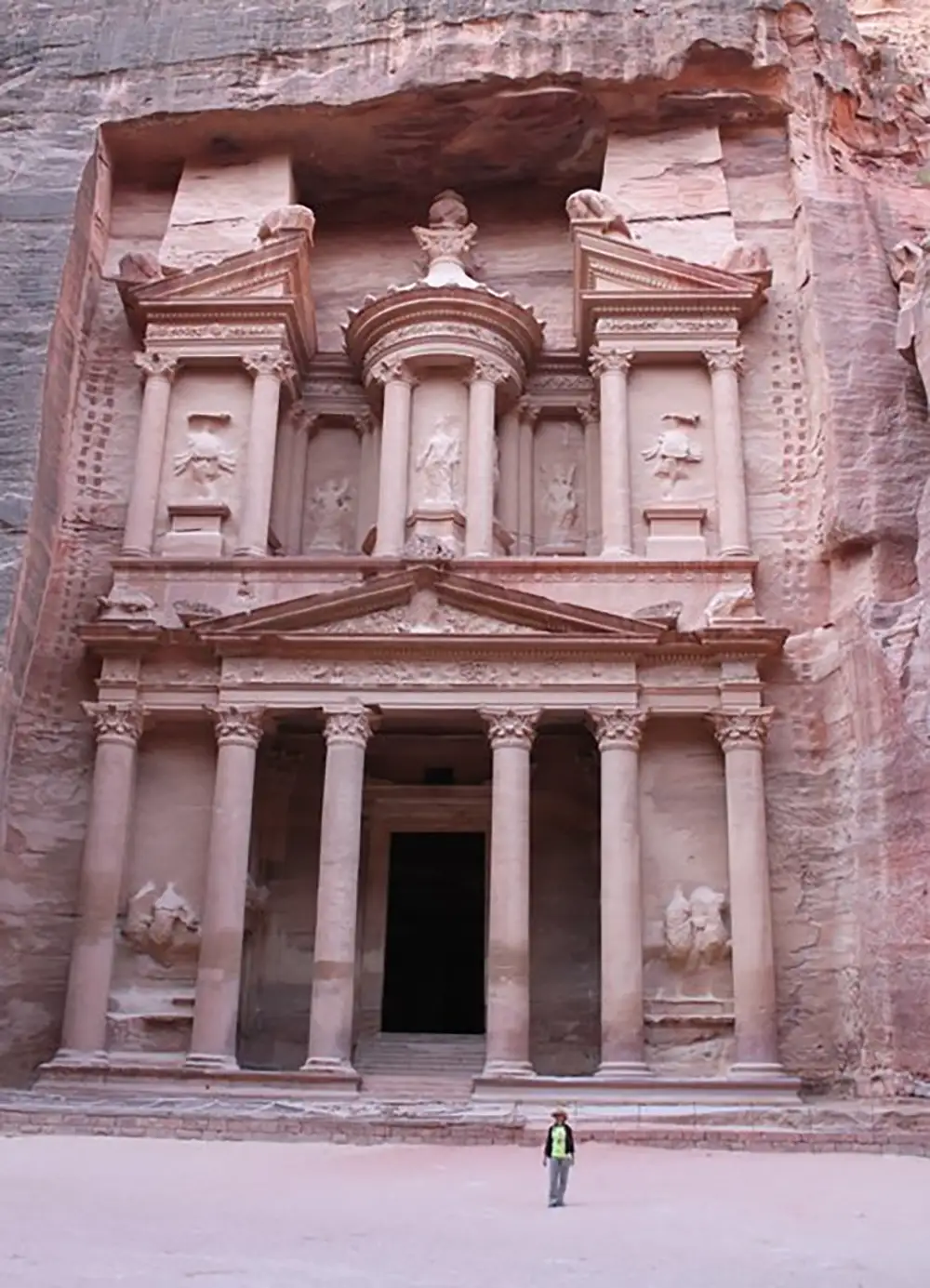 A person standing in front of a large facade with columns.