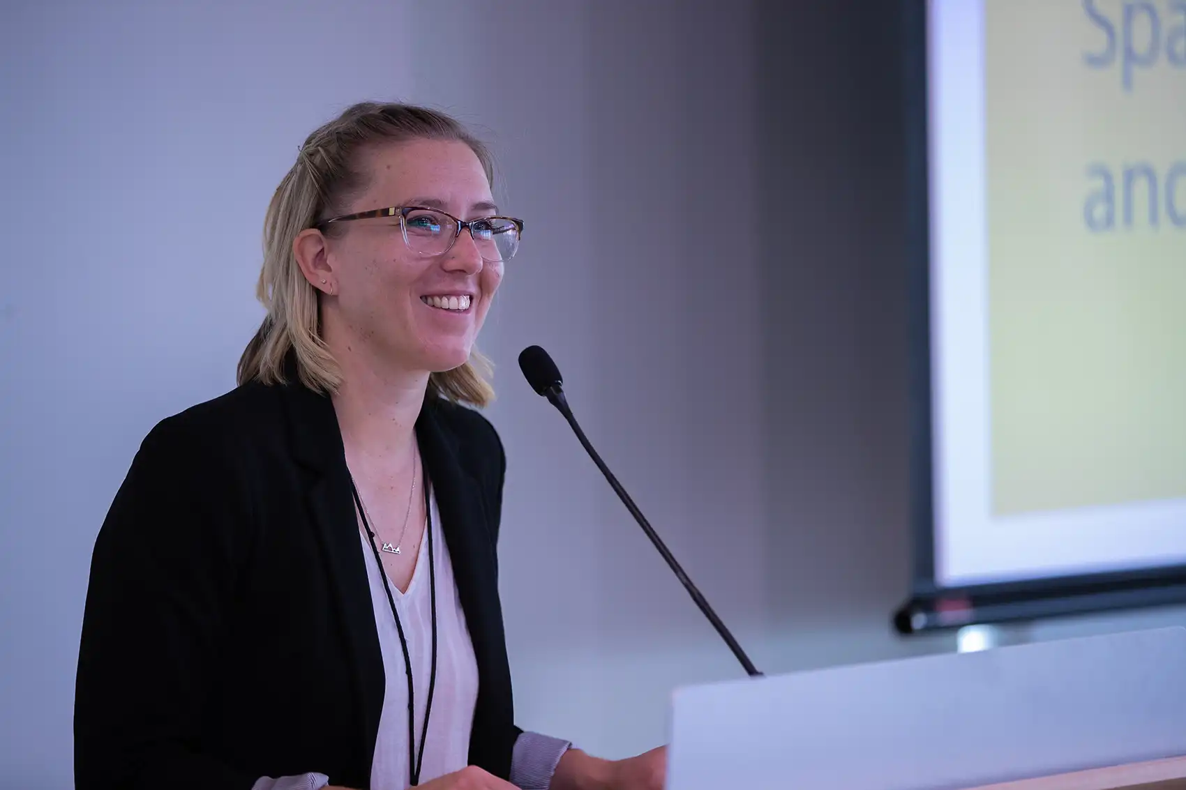Taylor smiles while standing behind a podium