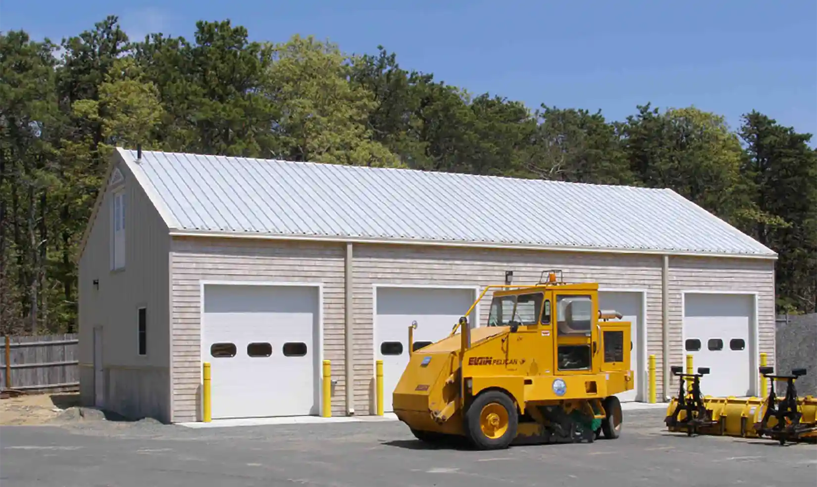 A street sweeper in front of a four-door garage.