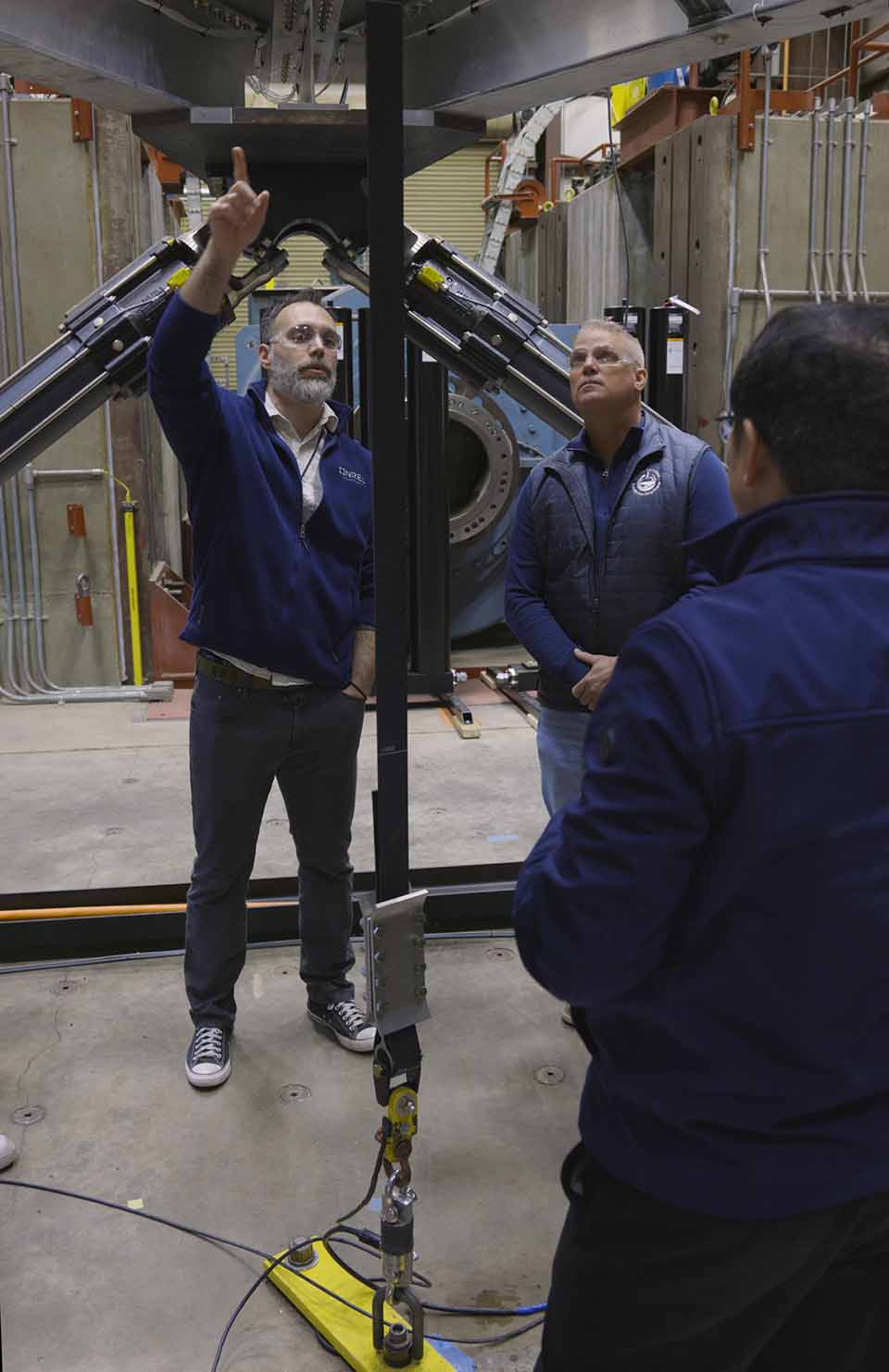 A photo of a group of people standing underneath large machinery.