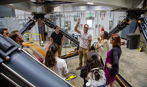 Continue reading about A photo of a group of people standing underneath large machinery.