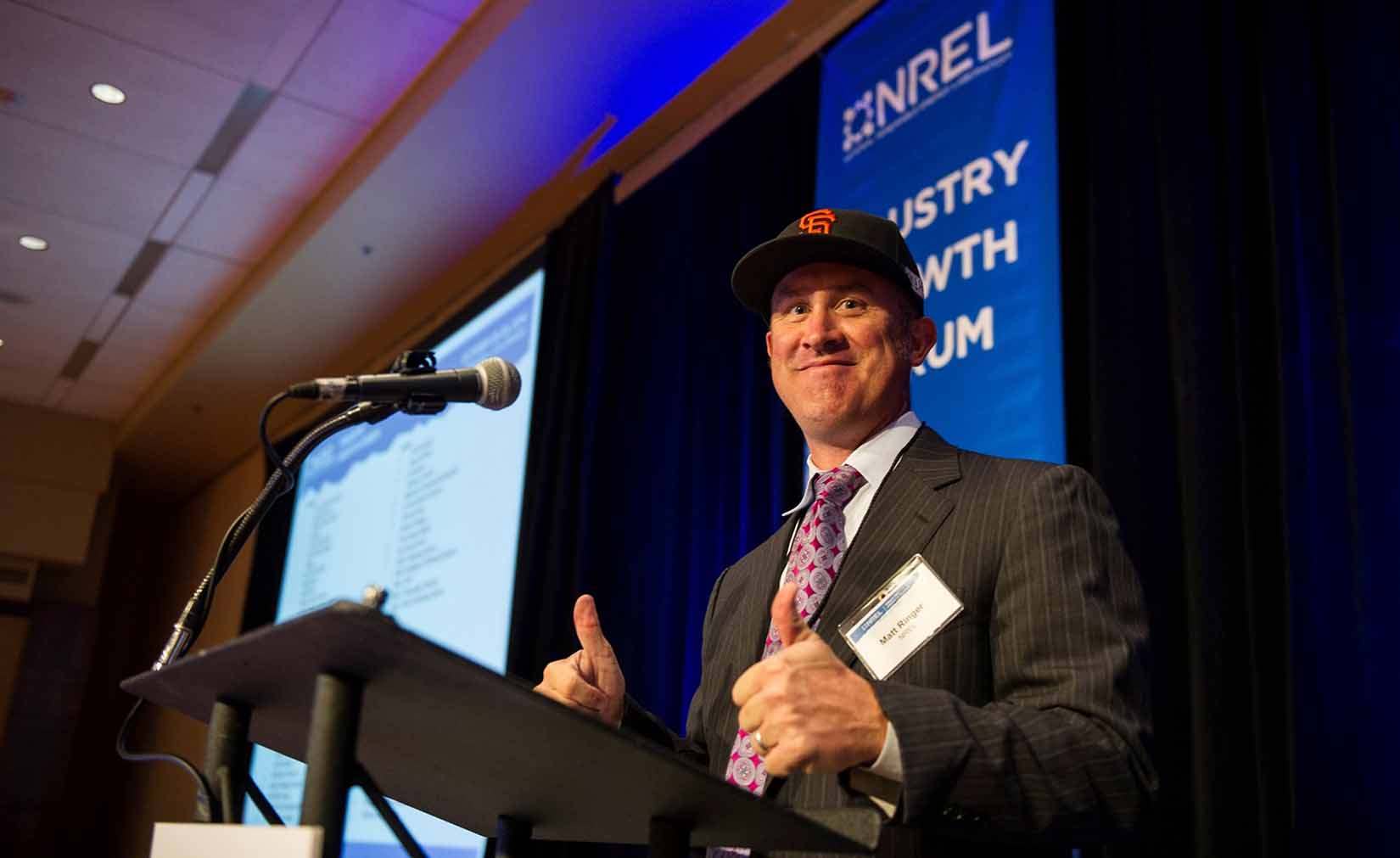 Ringer gives a thumbs up while standing behind a podium