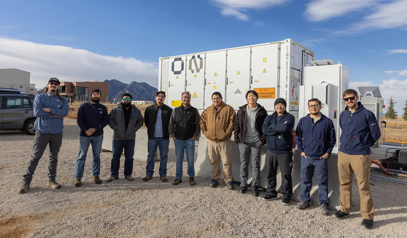 Ten people stand outside in front of a new medium-voltage AI uninterruptible power supply.
