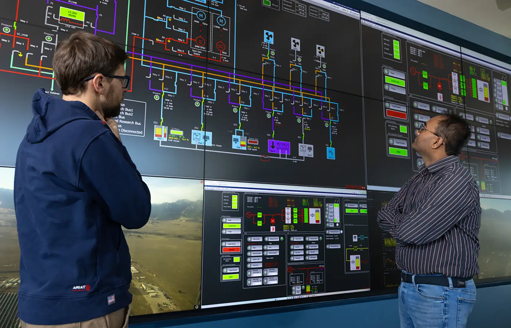 Two people look at graphics on a large screen.