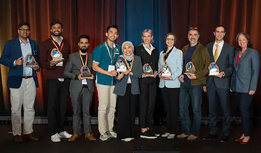 Continue reading about Ten people holding trophies standing on a stage.
