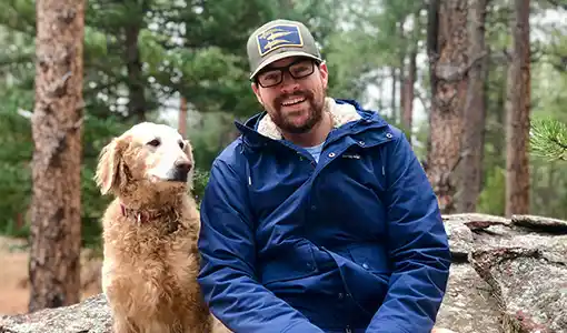 Trevor Martin hiking in the woods with his dog.