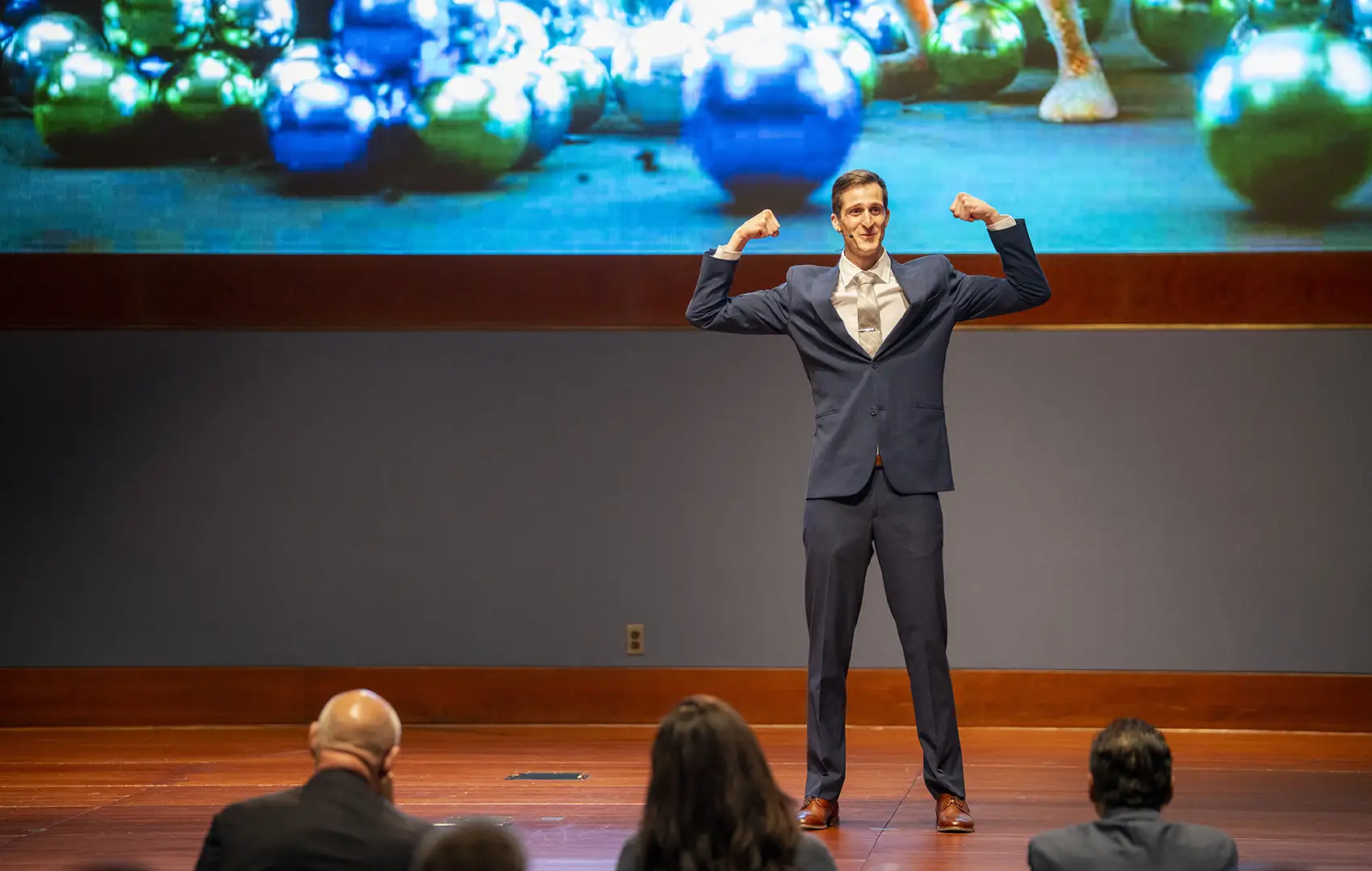 20260526-nlr-kalen-rasmussen-wins-energy-security-award-at-national-lab-research-slam-9793 A person in a suit flexes his arms on stage