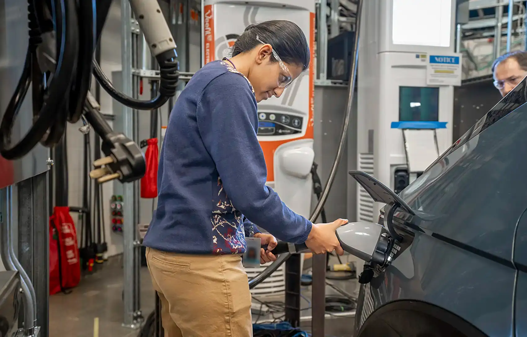 20260528-smart-energy-management-research-could-unlock-grid-flexibility-and-cost-savings-0060 A person plugs a charging cable into a vehicle in a lab.