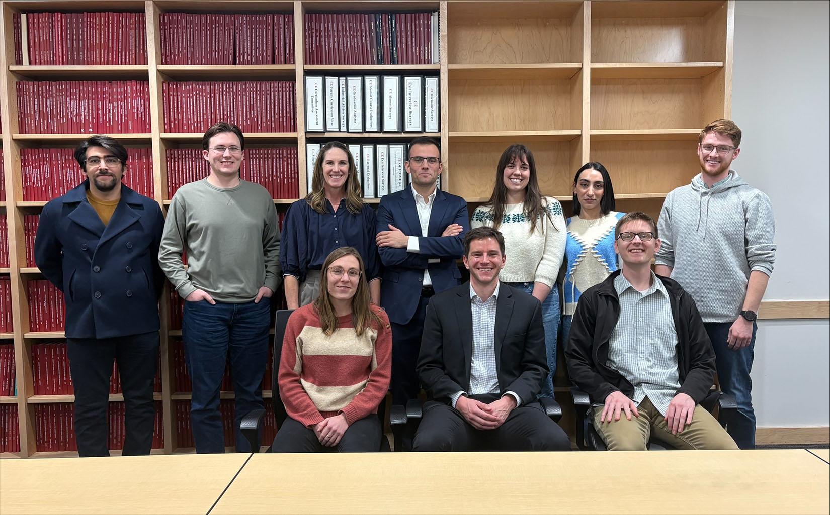 20260622-sienna-grid-modeling-team-puts-power-in-hands-of-people-utah-training 10 people posing in front of a large wall bookcase