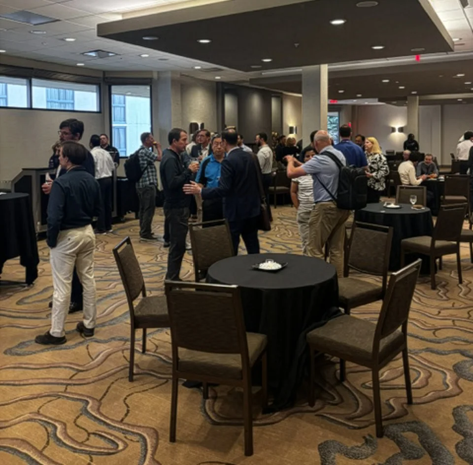 20260811-computing-facilities-can-save-big-and-keep-cool-by-looking-underground-3950 People standing and talking in a large room.