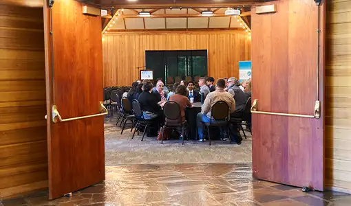 View through open doors of a small group of people seated around tables.