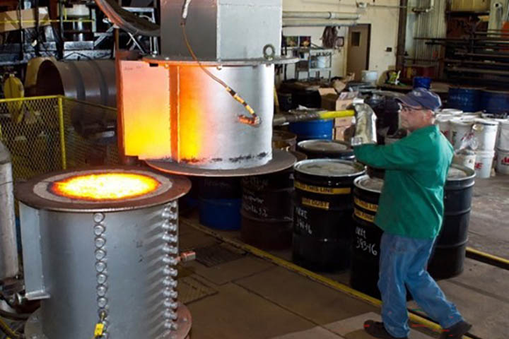from-nrri-flt Worker in safety gear operating a furnace with glowing molten metal at a metallurgical facility