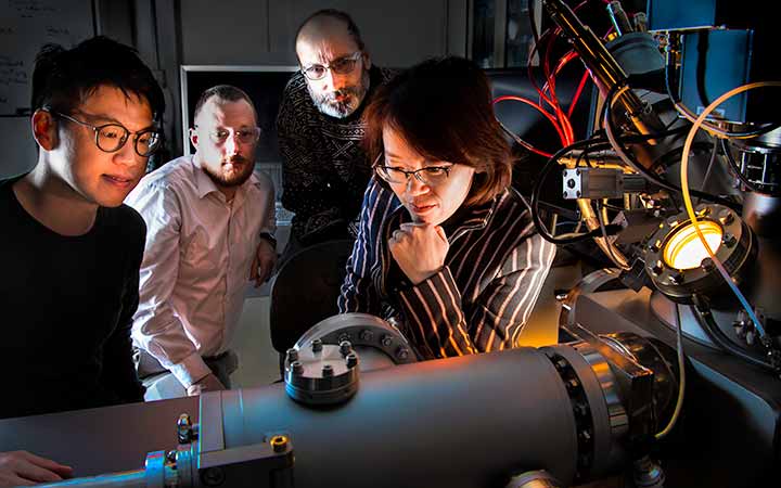 Four researchers working with a time-of-flight secondary ion mass spectrometry.