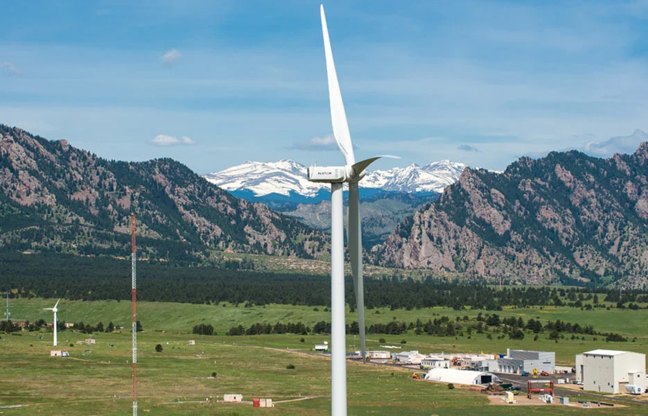 A wind turbine in a field with mountains in the background at NREL's National Wind Technology Center