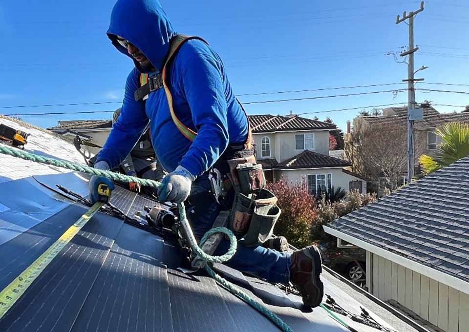 Installer measuring solar shingles on a roof