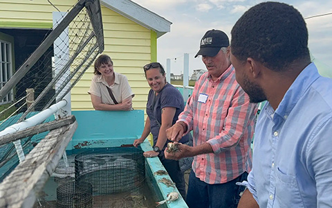 Four people talk as one man holds a crab.