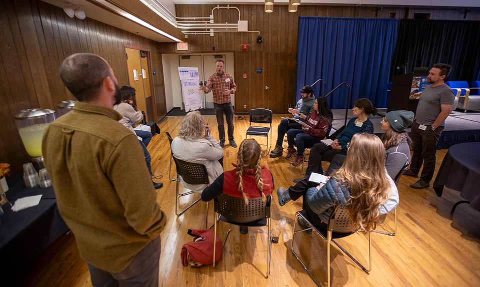 A group of people listening to a man speak.