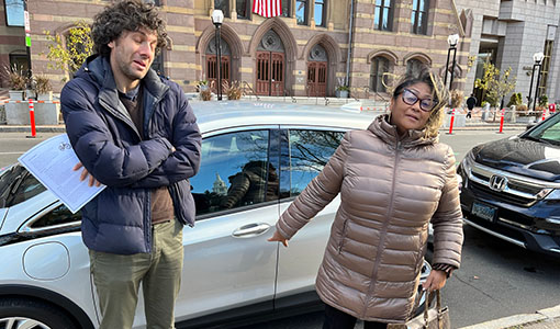 Continue reading about Two people stand in front of an electric vehicle.