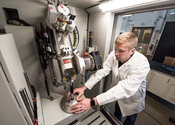 Man in white lab coat works with science equipment in a laboratory.
