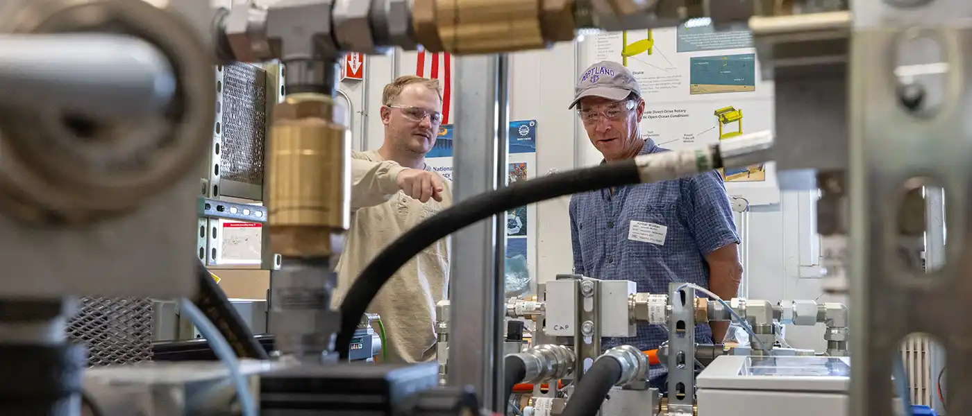 Two researchers examine water power equipment in a lab.