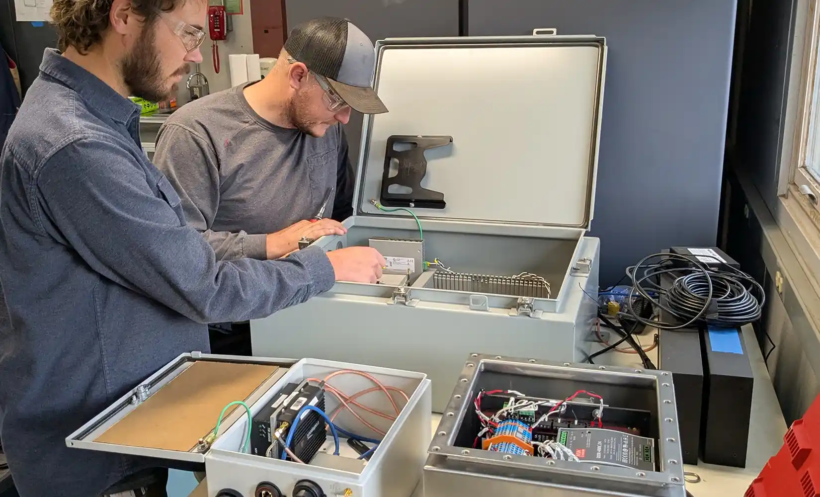 Two researchers look inside electrical box.