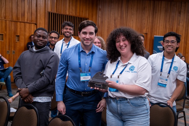 Group of people stand and smile while holding award