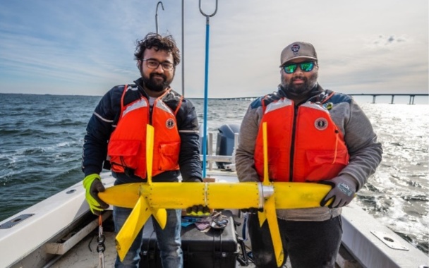 Two people on a vessel ready to deploy a marine energy device
