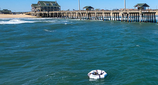 WEC device floating in ocean next to pier