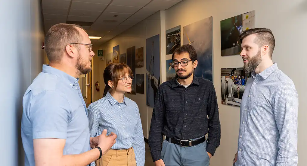 Four researchers talking in a hallway.