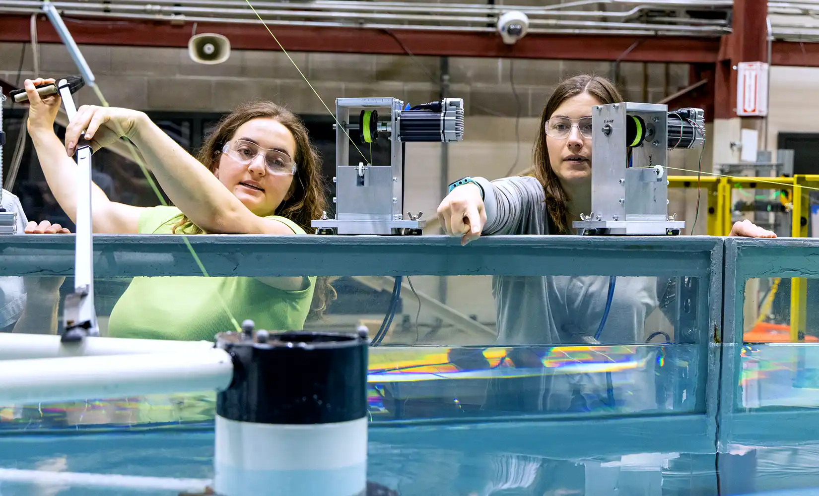 Nora Riedinger and another lab associate test device in wave tank.