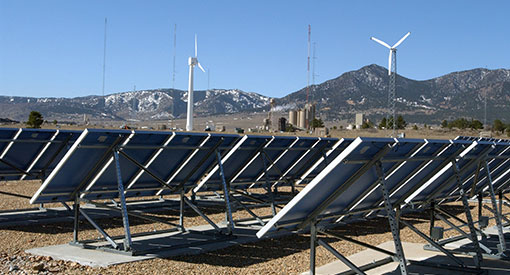 Solar panel array with wind turbines in the background