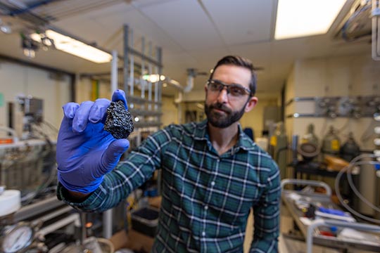 A researcher holding up a chunk of bio-coke.