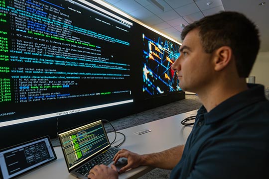 104900-flt A researcher looking at a large screen of code.