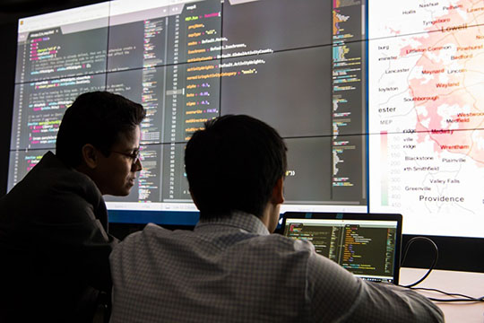 Two people looking at a data visualization on a large screen.