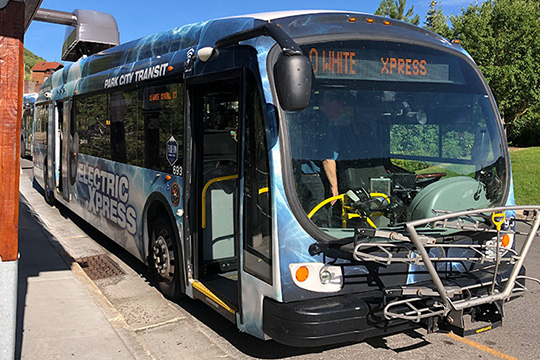 An electric public transportation bus at a bus stop.